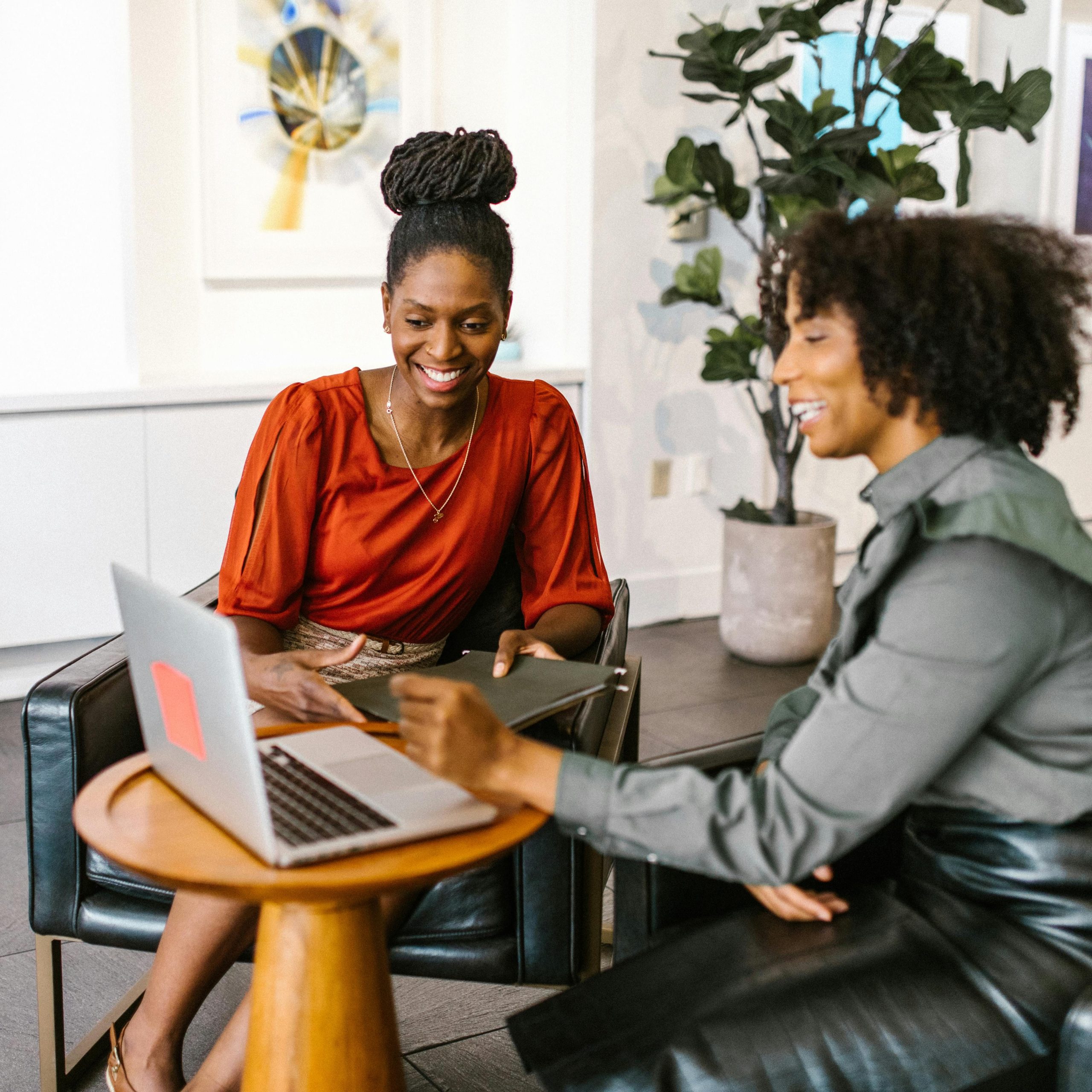 Two African American women collaborating on a business project in a modern office setting.