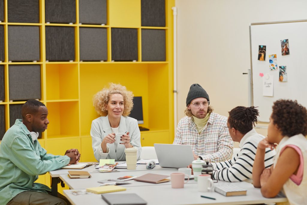 A diverse group of coworkers engaging in a meeting around a table in a modern office setting.